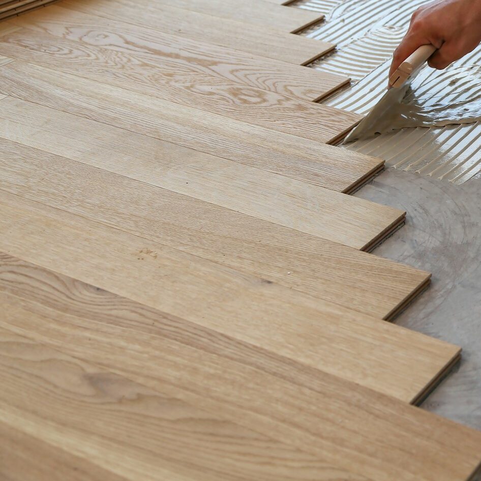 Male worker installing a wooden laminate flooring on his knees